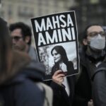 A woman shows a placard with a photo of of Iranian Mahsa Amini as she attends a protest against her death, in Berlin, Germany, Wednesday, Sept. 28, 2022.