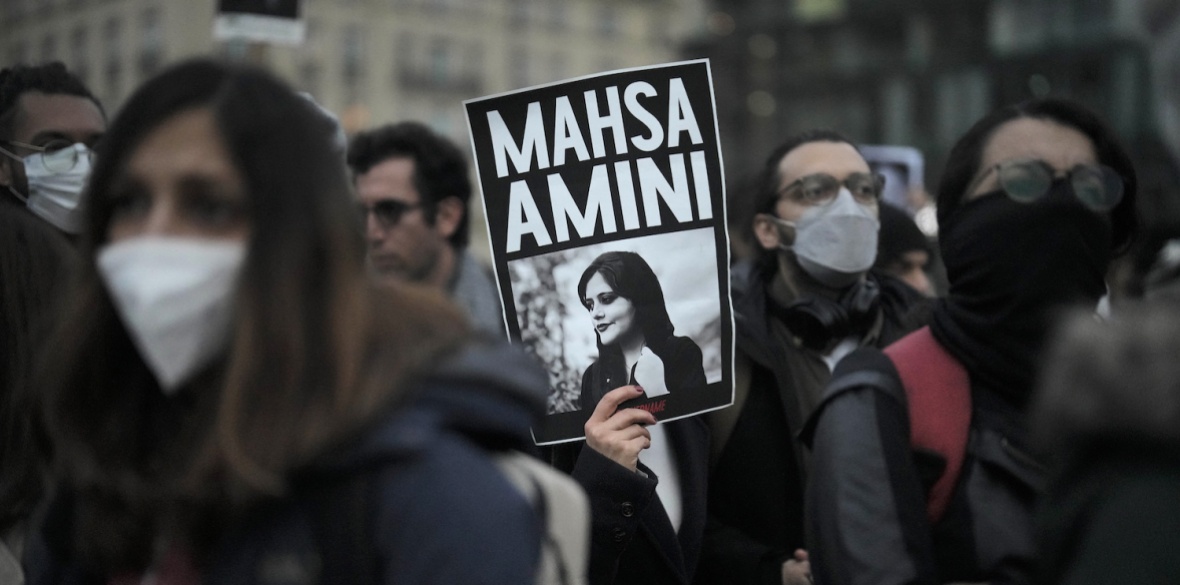 A woman shows a placard with a photo of of Iranian Mahsa Amini as she attends a protest against her death, in Berlin, Germany, Wednesday, Sept. 28, 2022.