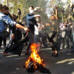 Iranian protesters set their scarves on fire while marching down a street on October 1, 2022, in Tehran, Iran. (Getty Images)