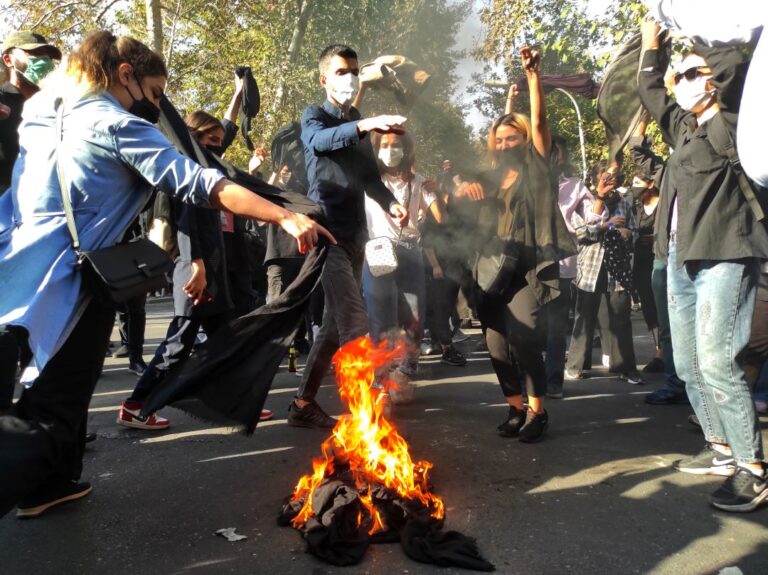 Iranian protesters set their scarves on fire while marching down a street on October 1, 2022, in Tehran, Iran. (Getty Images)