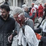 An elderly man is shepherded to safety in the bloody aftermath of an attack by US-Israeli warplanes on the area in and around Tehran's Enqelab (Revolution) Square on 3 March 2026, which left scores dead and gravely wounded as well as extensive damage to residences and civilian infrastructure | Tasnim News Agency | Creative Commons Attribution 4.0 International License